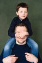 Boy is sitting on his fatherÃÂ¢s shoulders, covers dadÃÂ¢s face with his hands Royalty Free Stock Photo